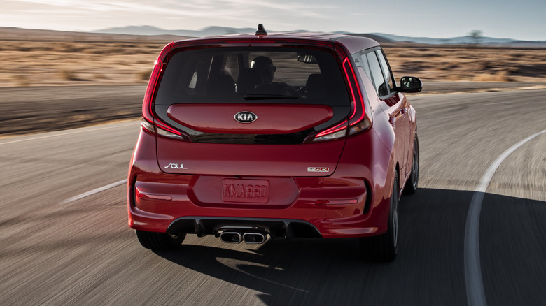 Rear view of a red 2021 Kia Soul driving on an open asphalt road