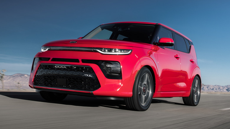 Front 3/4 view of a red 2021 Kia Soul driving at speed on an open asphalt road