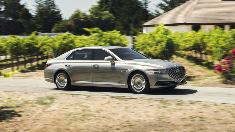 A silver 2021 Genesis G70 in motion on a road.