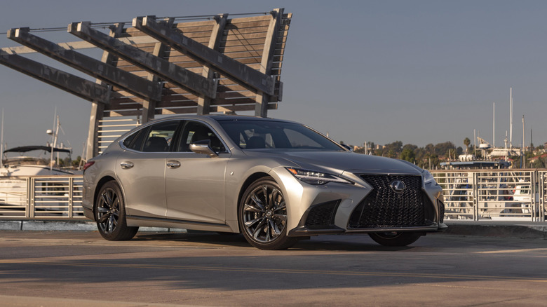 A silver 2021 Lexus LS 500 alongside a fence and boats.