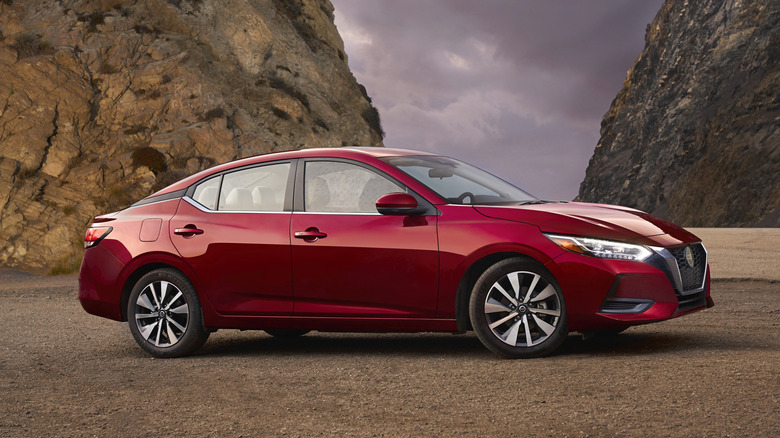 A red 2021 Nissan Sentra in front of rocky hills.