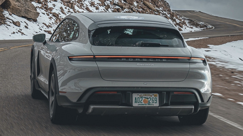 Rear shot of a chalk Porsche Taycan Cross Turismo driving up Pike's Peak.