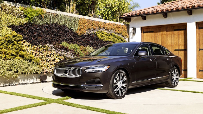 A brown 2021 Volvo S90 parked in front of a garage