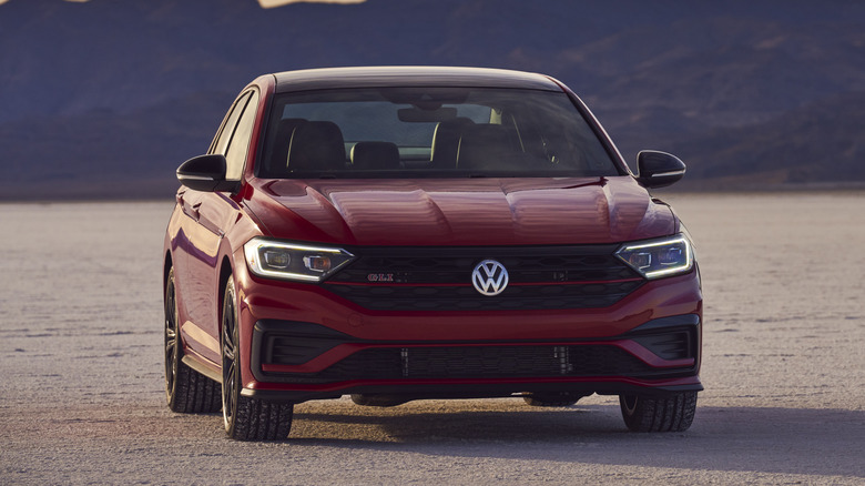 A red Volkswagen Jetta GLI parked on a salt flat in front of hills.