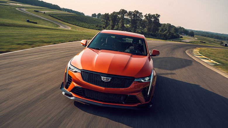 A front view of an orange 2022 Cadillac CT4-V Blackwing on a racetrack.