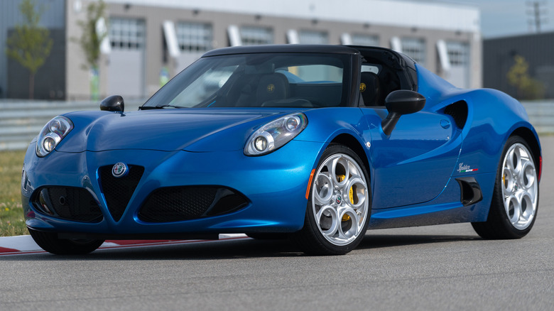 Blue Alfa Romeo 4C Spider, in third-quarter front view, parked on a race track.
