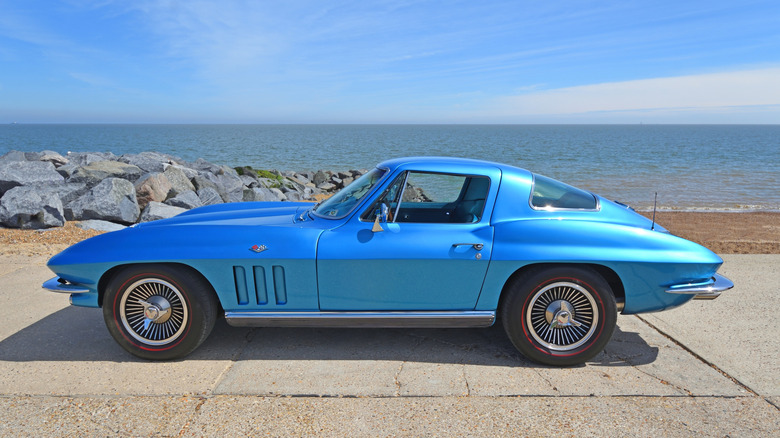 A bright blue Chevy C2 Corvette parked outside near a beach