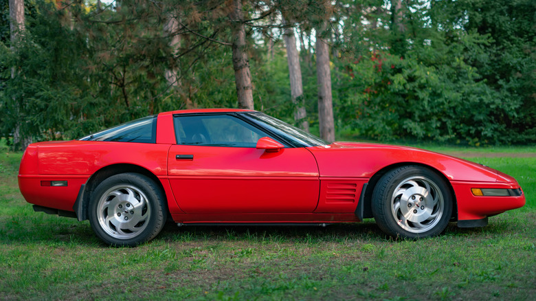 A red Chevy C4 Corvette parked in a forest opening
