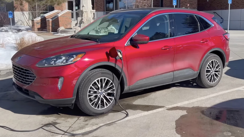A red 2021 Ford Escape plug-in hybrid electric vehicle with a charger plugged in