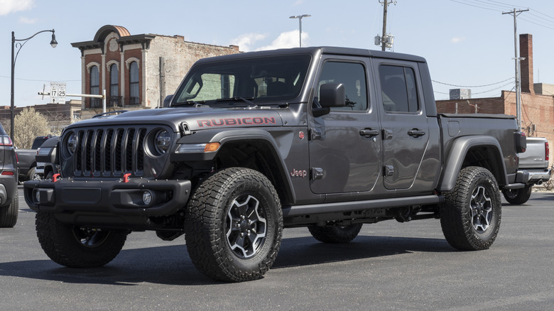 A dark gray 2021 Jeep Gladiator Rubicon parked in front of industrial-looking properties.