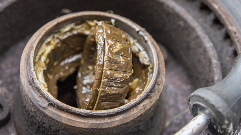 A wheel bearing with old grease viewed in a vehicle hub.