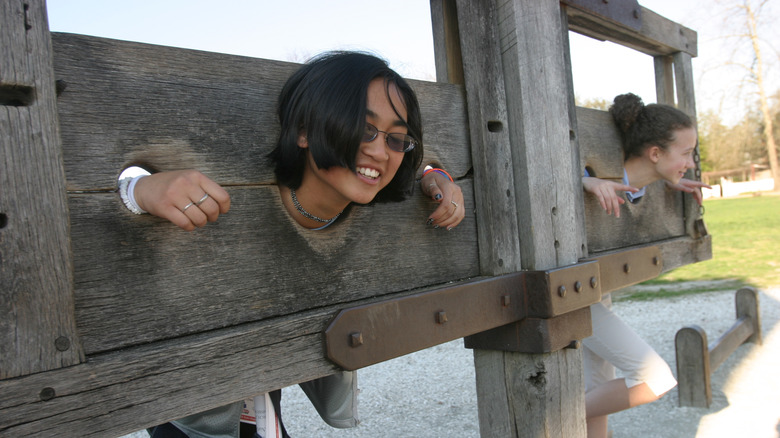 Kids put in to the pillory smiling at Colonial Williamsburg