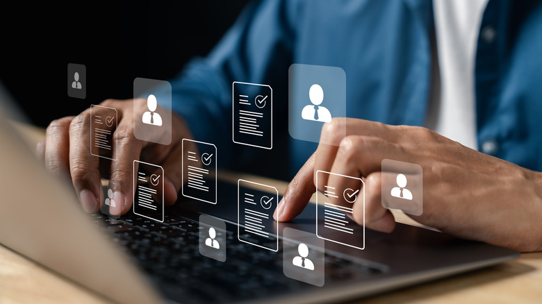 a set of hands hovering over a laptop with graphics of resumes laid over
