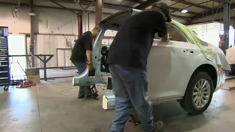 Workers rolling away the rear half of a car to convert into a limousine