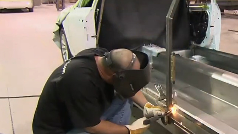 A technician welding the roof support structure of a limousine car