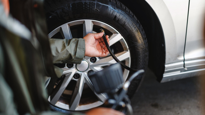 A person checking a tire's pressure on a car