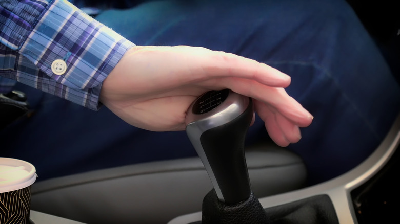 A person's hand on a manual car's gear shifter