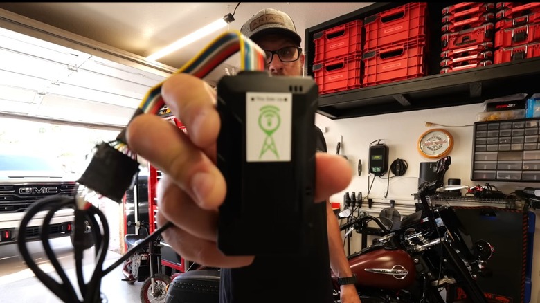 Man holds GPS tracker he found plugged into the ODB-II port of his pickup