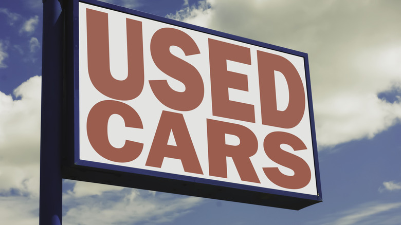 A used car sign with the sky in the background.