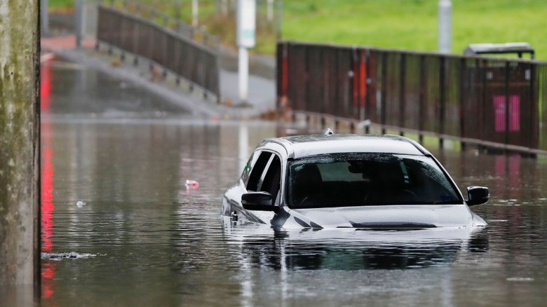 A car stopped in flood water with the windows open