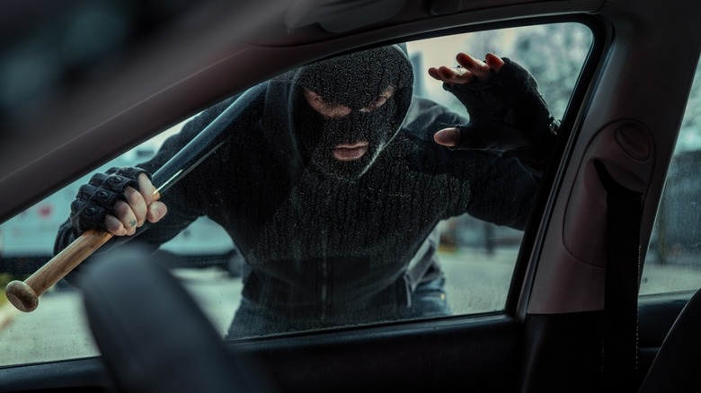 Thief with a baseball bat looking through a car window