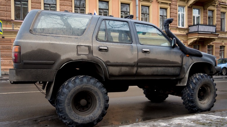 An SUV with a raised suspension and big off-road tires parked on a city street