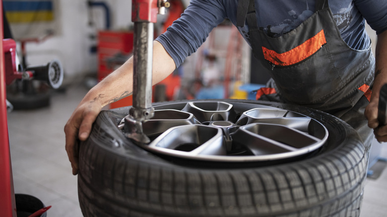A mechanic installs a tire on a wheel