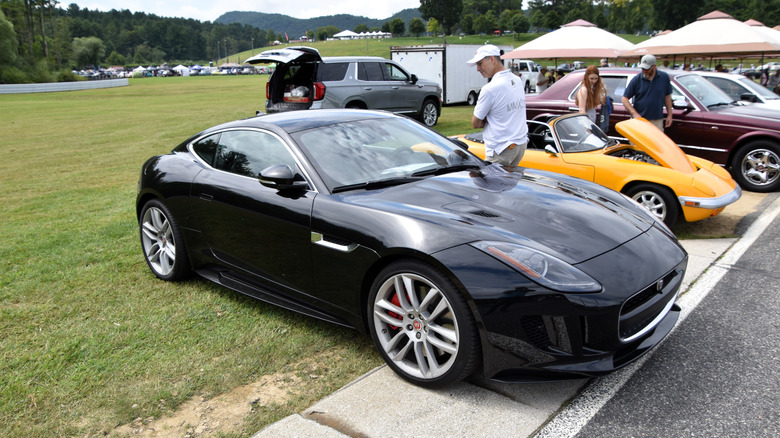 A black Jaguar F-Type R Coupé parked in a row of cars