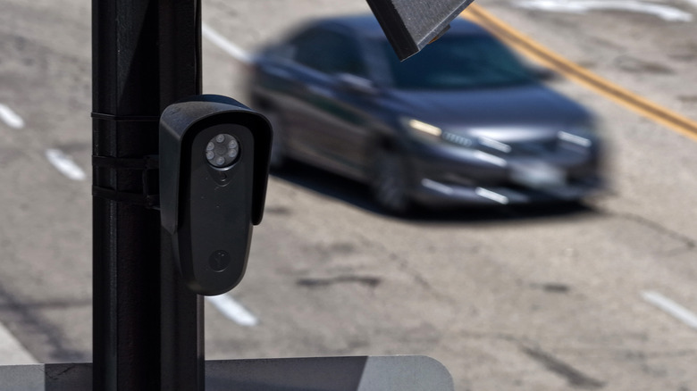 A Flock camera with a moving car in the background.