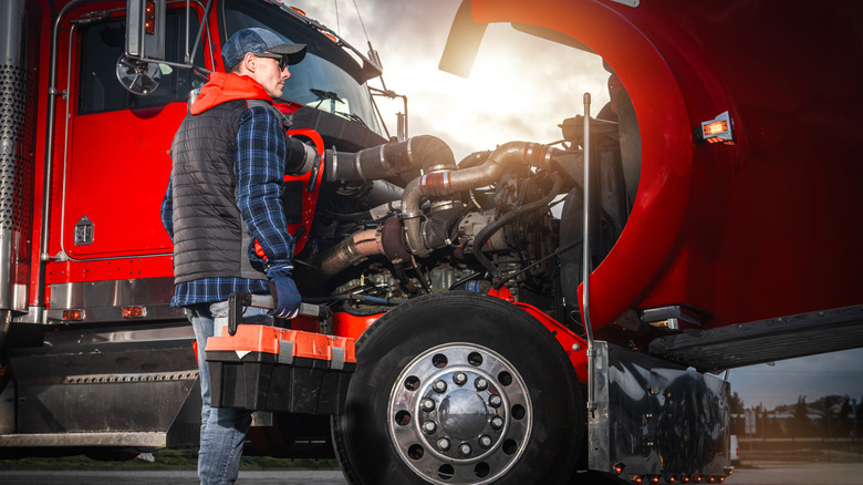 A technician approaching a truck with a tool kit.