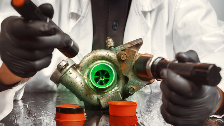 A technician inspecting a damaged turbocharger