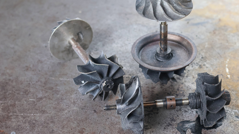 Three damaged turbocharger turbine blades on a table