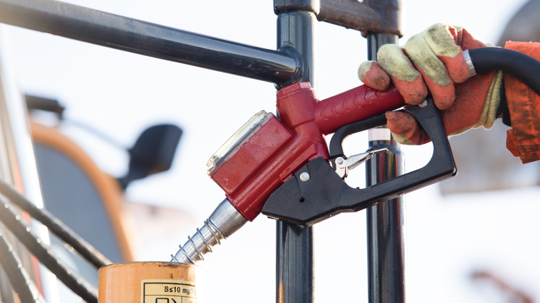 An excavator driver filling up the machine with diesel fuel