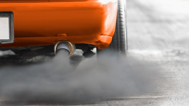 Orange diesel vehicle emitting black smoke from the tailpipes