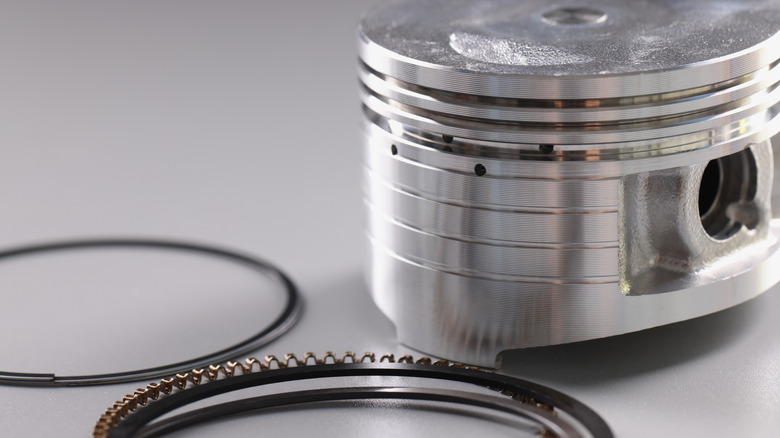 A piston with three piston rings and new rings in the background