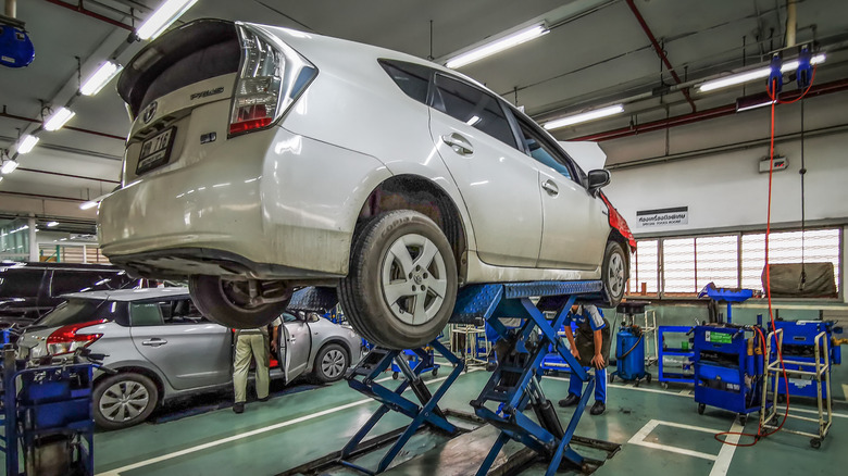 A white Toyota Prius hybrid car being checked at a service station