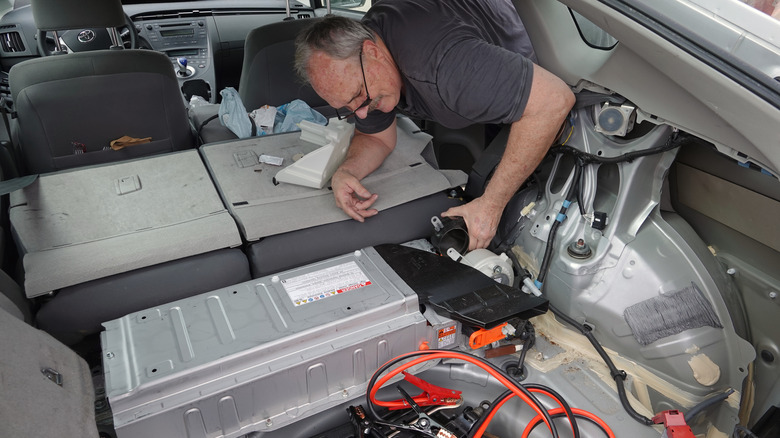 A technician inspecting the battery pack of a Toyota Prius hybrid car