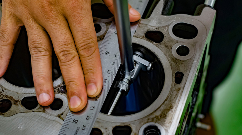 A technician measuring an engine cylinder bore using a micrometer