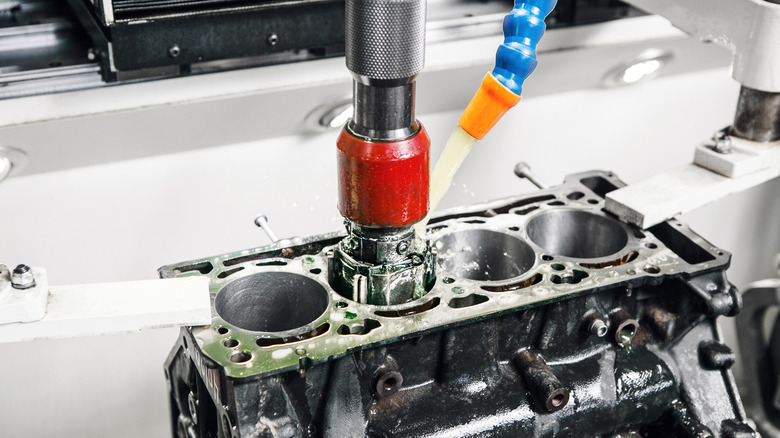 A CNC machine honing the cylinder bore of a four-cylinder engine