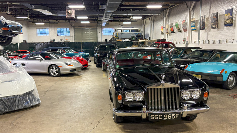 A view of a car collection featuring supercars and classic cars, displayed in a secure industrial-style garage with automotive memorabilia.