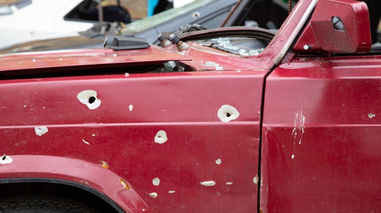 A red vehicle riddled with bullet holes