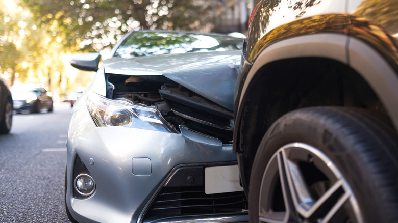 A car with a crunched front end and an SUV involved in a collision