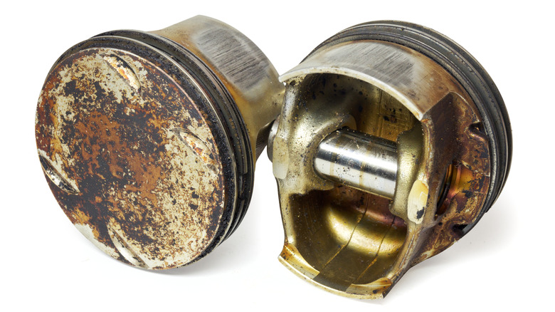 Engine pistons from both sides, with flat head surface full of sludge deposits