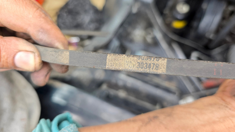 Mechanic holding a worn fan belt