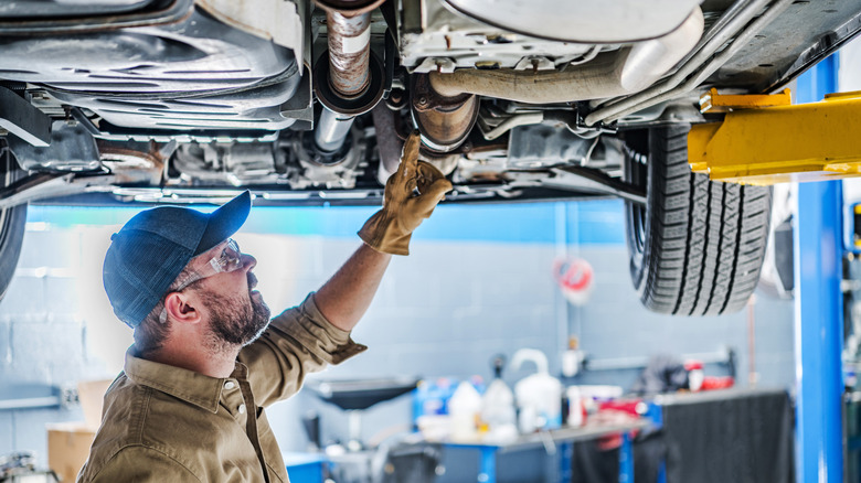Mechanic checking the catalytic converter under a vehicle