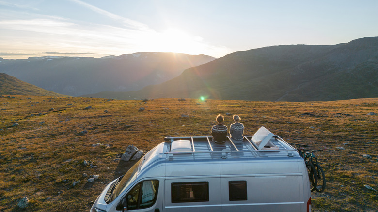 Two campers sitting on the roof of their overlanding van