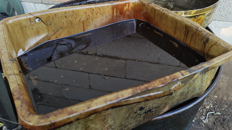 A tray of used, discarded engine oil with a deep, dark brown color