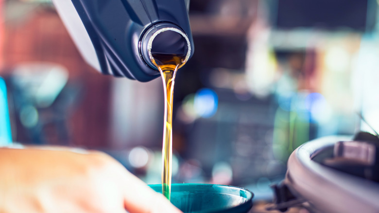 Mechanic using a funnel to pour fresh oil into a car's engine
