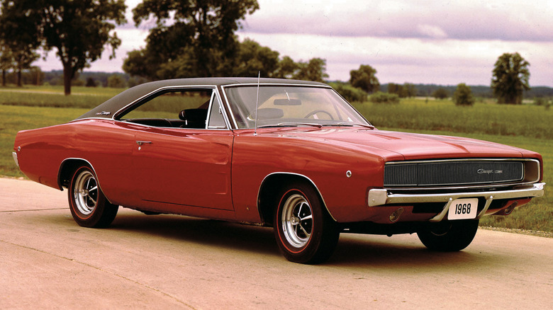 A burnt-orange1968 Dodge Charger R/T parked in front of a grassy field.