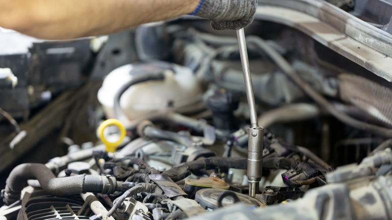 A mechanic installing a new spark plug into the engine
